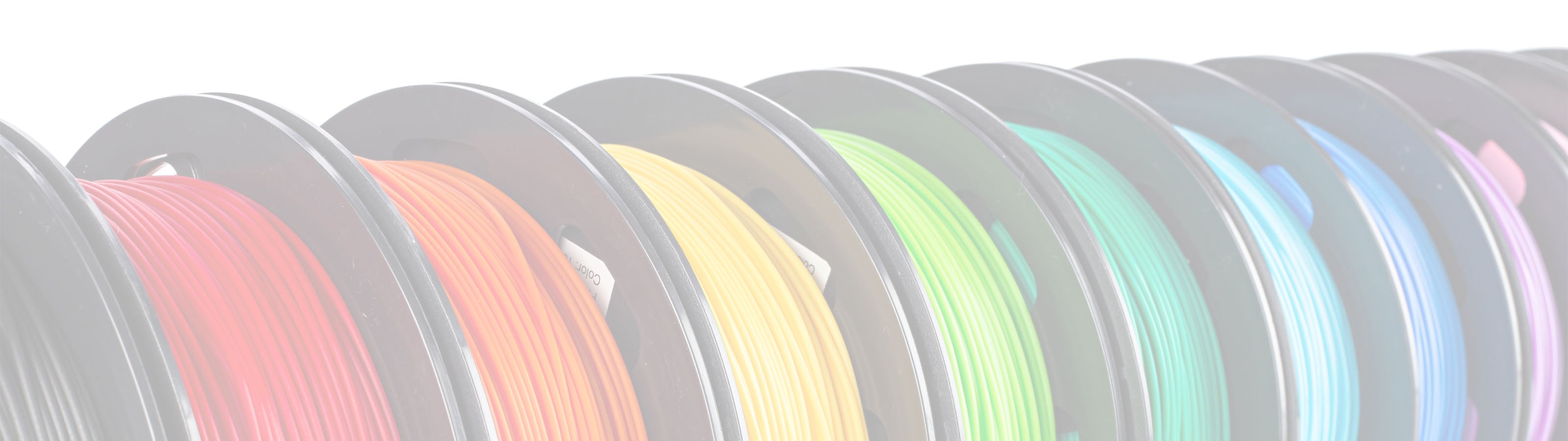 Image of multiple spools of 3D printer filament arranged side by side. The filaments are in various colors including red, orange, yellow, green, blue, and purple. The image has a soft, bright lighting effect.
