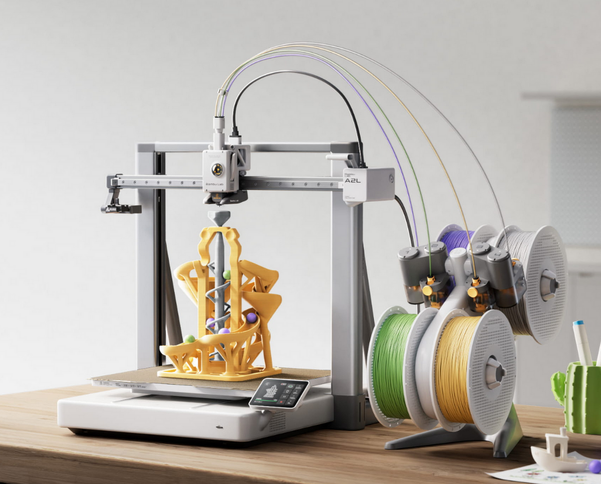 Bambu Lab A2L 3D printer with yellow printed model, filament spools, and control screen on wooden desk